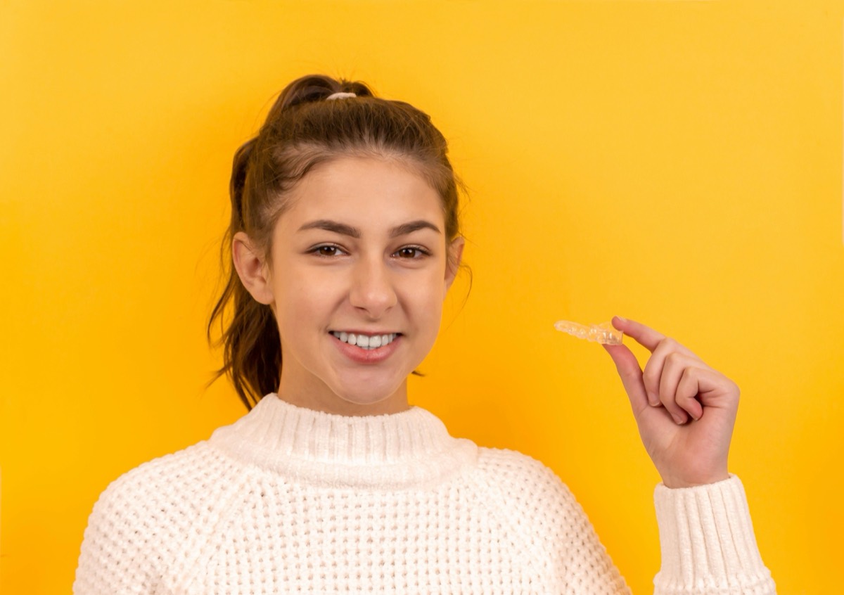 Patient holding an orthodontic retainer after braces treatment